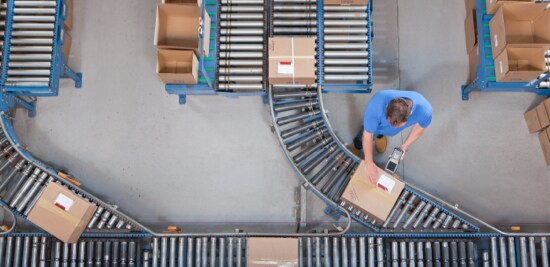 Boxes moving along conveyors in a fulfillment centre.
