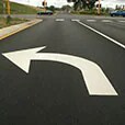 Large left-turn arrow on pavement in road’s turn lane.