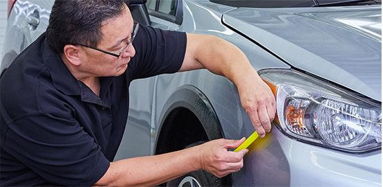 Man using a squeegee on 3M™ Paint Protection Film installation.
