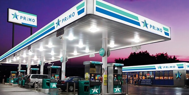 Gas station with vivid backlit blue and green graphics and signage.
