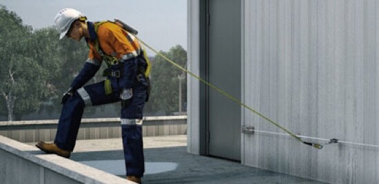 Un travailleur attaché à un système horizontal qui regarde par-dessus le bord d’un bâtiment.
