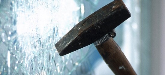 Un marteau frappe une fenêtre en la fissurant sans la briser.
