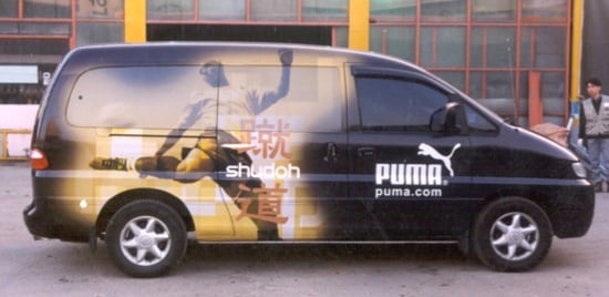 Une fourgonnette recouverte d'une pellicule de placage interchangeable représentant un joueur de football frappant un ballon.
