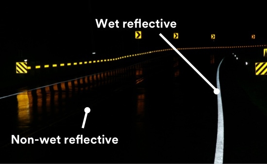 A bend in a wet rural road at night.
