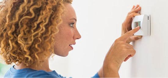 A woman adjusting the thermostat.

