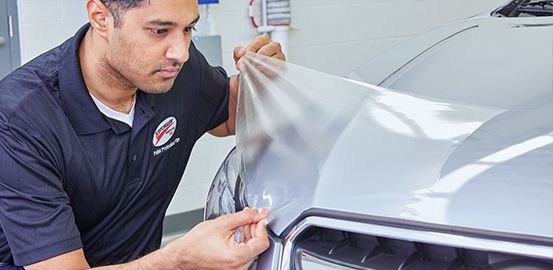 Man installing 3M™ Paint Protection Film on partial hood.
