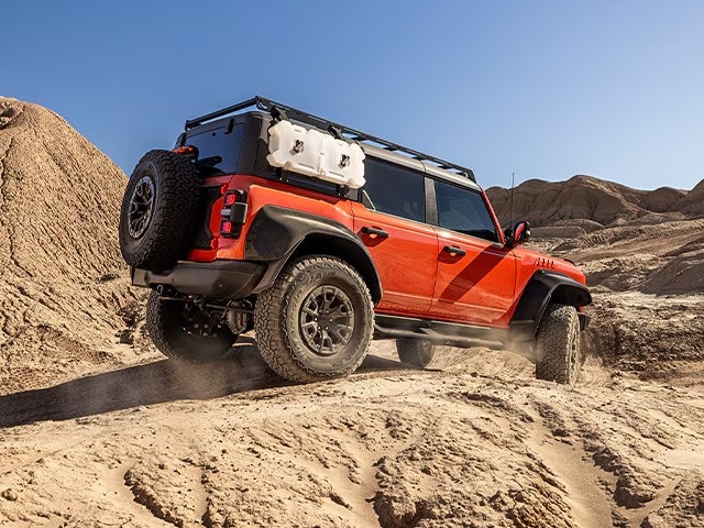 SUV with habanero red protection wrap film driving offroad in the desert.
