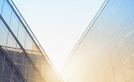 Rayons de soleil embrasant des bâtiments anguleux aux façades vitrées.
