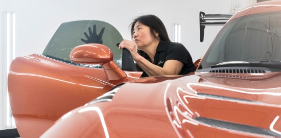 Auto technician installing window tint on the inside of a passenger car window.
