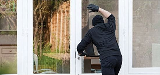 A robber looking into a glass door.
