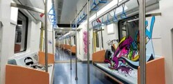 Le mur intérieur et le siège d’une voiture de métro couverts de graffitis.
