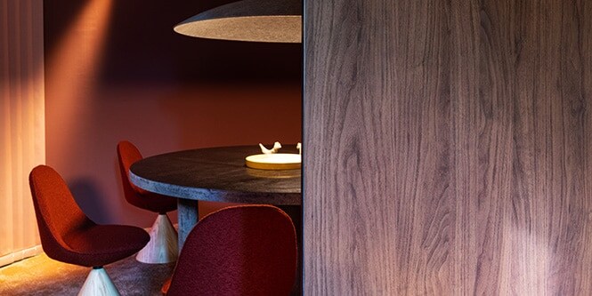 Salle à manger ronde, mettant en scène une table ronde habillée d’une finition architecturale métallique DI-NOC 3M, au cœur de murs mates et de finitions architecturales en bois sombre.
