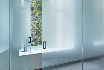 Murs et portes en verre d’une salle de conférence rehaussés d’un effet dégradé givré grâce aux finitions pour verre FASARA.
