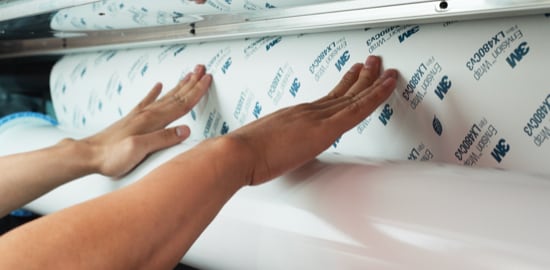 Personne chargeant un rouleau de Pellicule pour impression numérique Envision(MC) 3M(MC) sur un rouleau pour l’impression. 
