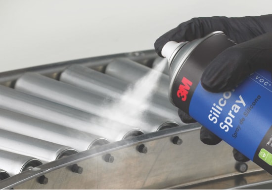 A maintenance and cleaning spray adhesive being applied to a metal surface.