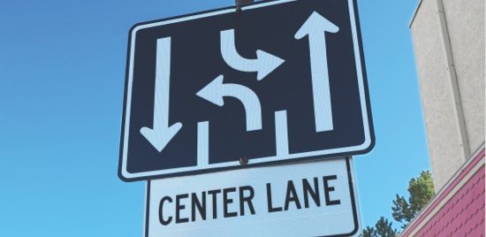 Stacked road signs, one depicting two driving lanes and one turn lane, and the other with the words 'center lane'.
