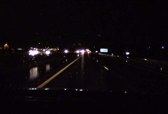 A video still of a wet highway at night.
