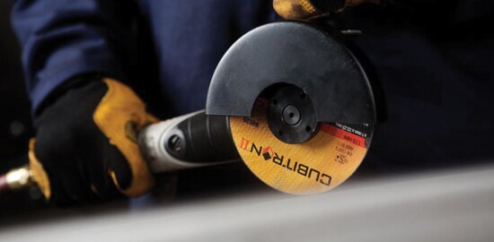 The hands of a worker holding a power tool with a 3M™ Cubitron™ II Cut-Off Wheel.
