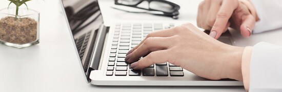 A woman's hands resting on a laptop keyboard.
